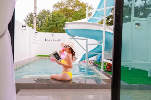 a woman in a bikini sitting in a pool reading a book at บ้านพักเขาใหญ่ ลูกแก้วพูลวิลล่า Lookkaew Pool Villa Khaoyai in Ban Rai Khlong Sai