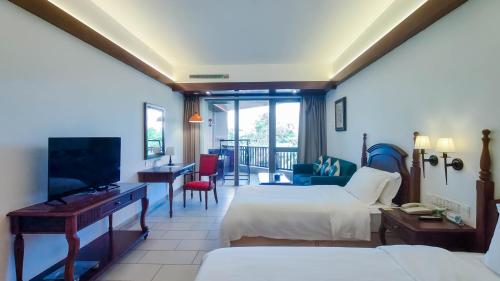 a hotel room with two beds and a television at Timton Fuhe Hotel, Sanya in Sanya