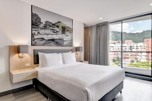 a bedroom with a large bed and a large window at Loft Home Suites 118 By gA in Bogotá