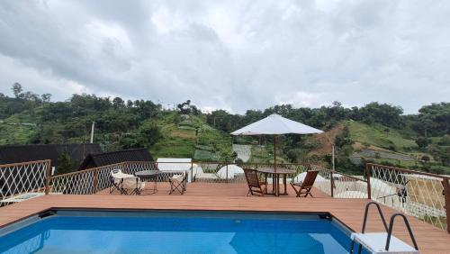 a deck with a pool and a table and an umbrella at Mahkota Sangkuriang Bandung in Bandung