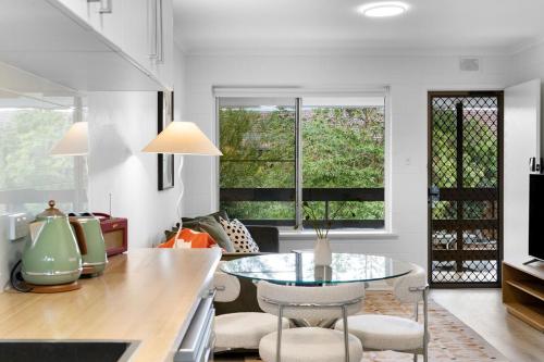 a kitchen with a table and chairs and windows at Jazz at Unley in Unley