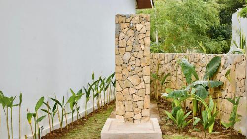 a stone pillar in a garden next to a stone wall at Malasama Suites Hotel in Kuta Lombok