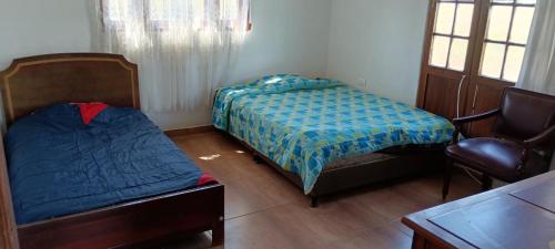 Estación El SaltoにあるCasa san Antonioのベッドルーム1室(ベッド2台、椅子、テーブル付)