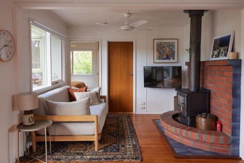 una sala de estar con un sofá y una chimenea en Lohr Ave Holiday Home, en Inverloch