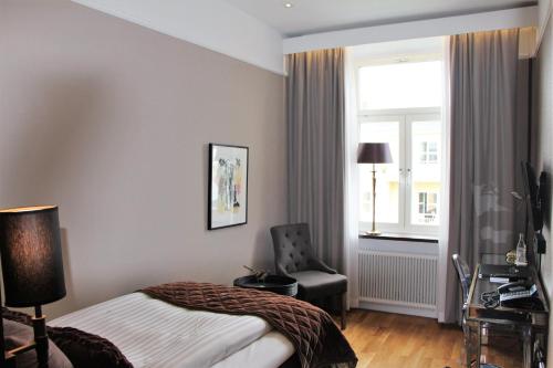 a bedroom with a bed and a chair and a window at Continental du Sud in Ystad