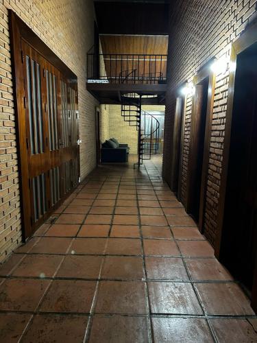an empty hallway with a brick wall and a staircase at Quarto privado no Centro in Botucatu