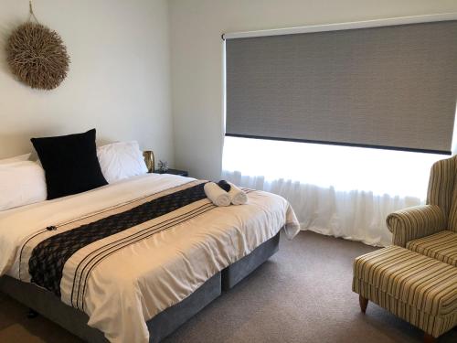 een slaapkamer met een bed, een raam en een stoel bij Lbarza Stylish 3BR Central Serviced Apartment in Shepparton