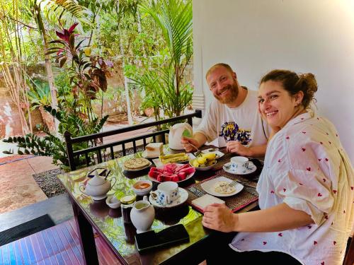 a man and a woman sitting at a table with food at Priyavimana resort in Habarana