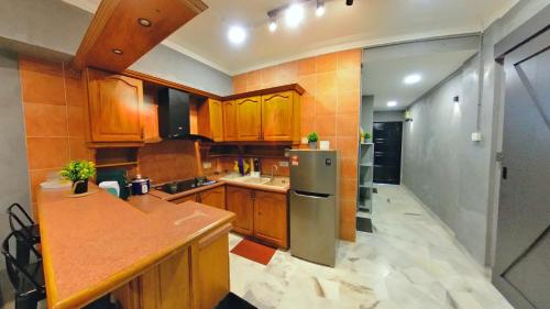 a kitchen with wooden cabinets and a stainless steel refrigerator at 2-9pax GFloor PRIVATE BEACH, WATERSPORT, POOL, FREE BBQ Set, Wifi, 50"TV in Port Dickson