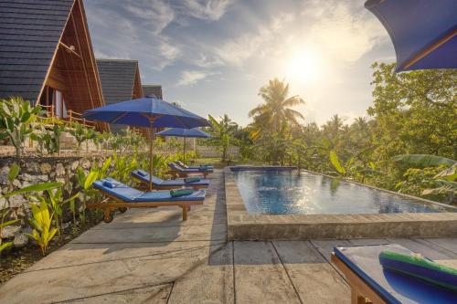 eine Reihe von Stühlen mit Sonnenschirmen neben einem Pool in der Unterkunft Belangga Cottage in Nusa Penida