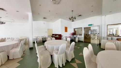 a banquet hall with white tables and white chairs at 2-9pax GFloor PRIVATE BEACH, WATERSPORT, POOL, FREE BBQ Set, Wifi, 50"TV in Port Dickson