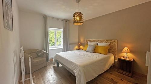 a bedroom with a bed and a chair and a window at Le vieux tilleul in Bessines-sur-Gartempe