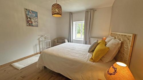 a bedroom with a large white bed with a window at Le vieux tilleul in Bessines-sur-Gartempe