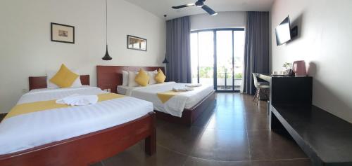 a hotel room with two beds and a desk at Siem Reap Tevi Residence in Siem Reap