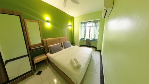 a small green bedroom with a bed and a mirror at 2-9pax GFloor PRIVATE BEACH, WATERSPORT, POOL, FREE BBQ Set, Wifi, 50"TV in Port Dickson