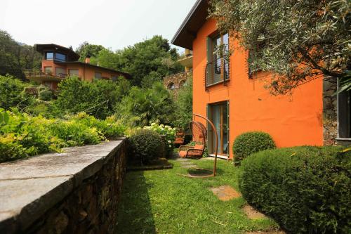 an orange house with a retaining wall and a garden at Villetta Isabella in Menaggio