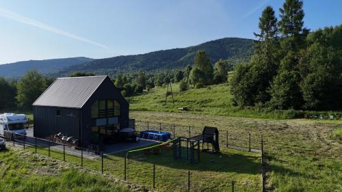 ein kleines Haus mit einem Spielplatz auf einem Feld in der Unterkunft Stodoła pod Bacówką Zawoja Sauna Jacuzzi in Skawica