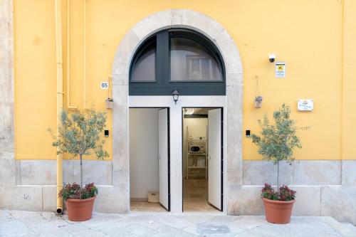 an entrance to a yellow building with two potted plants at Desideri di Puglia in Barletta