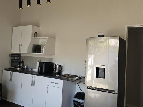 a kitchen with white cabinets and a stainless steel refrigerator at Lanina Garden Unit in Johannesburg