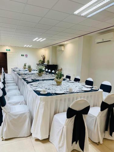 a long table in a room with white tables and chairs at Hotel Argento Zacatecas in Zacatecas