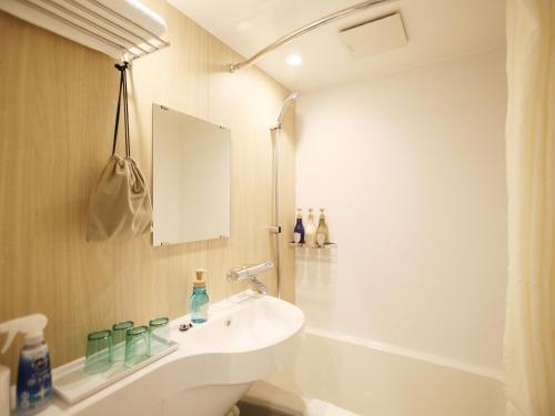 a white bathroom with a sink and a tub at Ishigakijima Hotel Cucule in Ishigaki Island