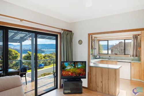 a living room with a tv and a large window at Inlet Views at 20 The Loop in Narooma