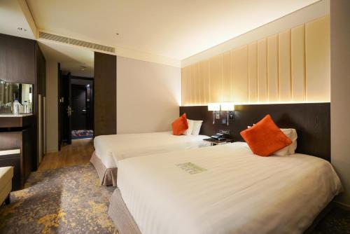 two beds in a hotel room with orange pillows at Solaria Nishitetsu Hotel Seoul Myeongdong - Renovated in 2025 in Seoul