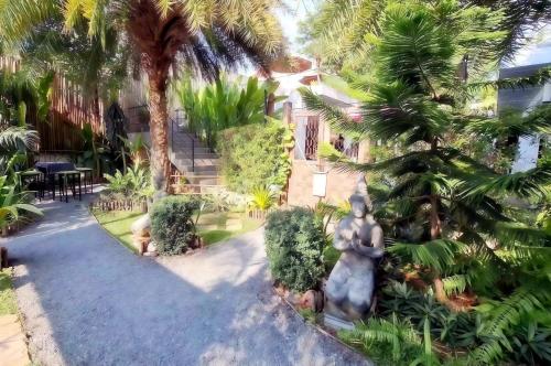 a statue in the middle of a courtyard with palm trees at Kana Hotel Phuket普吉岛卡娜酒店 in Rawai Beach