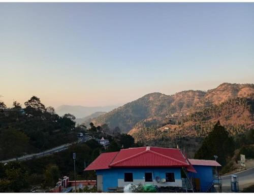 a house with a red roof on top of a mountain at Sumangalam Homestay सुमंगलम होमस्टे in Devaprayāg