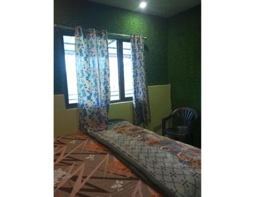a bed in a room with green walls and a window at Sumangalam Homestay सुमंगलम होमस्टे in Devaprayāg