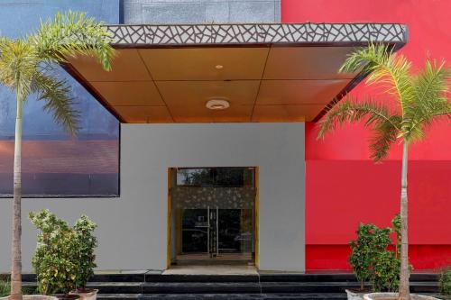 a building with palm trees in front of it at Super Townhouse Oak Anu Hospital Elur Road Formerly Grand Tankasala in Gunadala