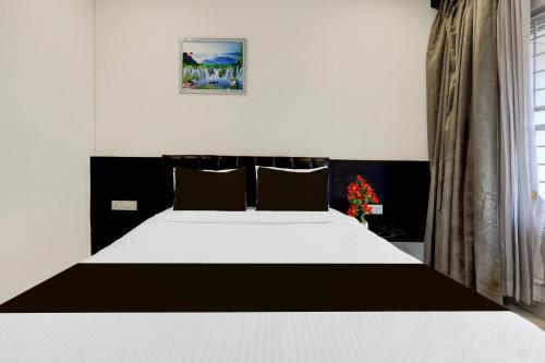 a bedroom with a black and white bed and a window at Super Townhouse Oak Anu Hospital Elur Road Formerly Grand Tankasala in Gunadala
