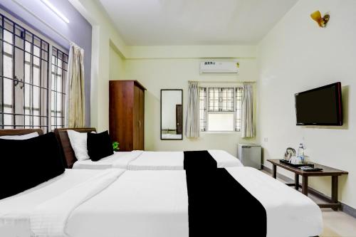 a bedroom with two white beds and a television at Super Collection O Begumpet Formerly Alpine Glow Sunrise in Hyderabad