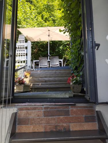 an open door to a patio with two chairs and an umbrella at les filatures in Saint-Vincent-de-Reins