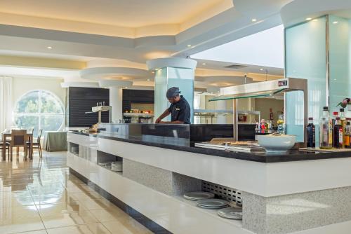 Un homme debout derrière un comptoir dans une cuisine dans l'établissement FERGUS Club Europa, à Paguera