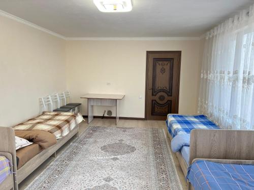 a room with two beds and a table in it at Tunduk Guest House in Kochkor