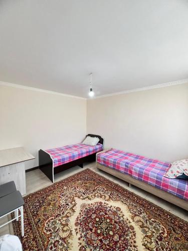 a room with two beds and a rug at Tunduk Guest House in Kochkor