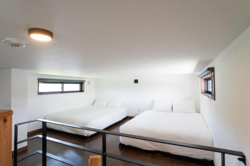 two beds in a room with white walls at Cyclo Villa - JUNGLIA15分! 美ら海25分! ビーチ古宇利島すぐ! BBQ無料貸出! in Nago