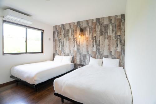a bedroom with two beds and a window at Cyclo Villa - JUNGLIA15分! 美ら海25分! ビーチ古宇利島すぐ! BBQ無料貸出! in Nago