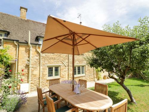 a wooden table with an umbrella in a garden at Wyncliffe in Chipping Campden