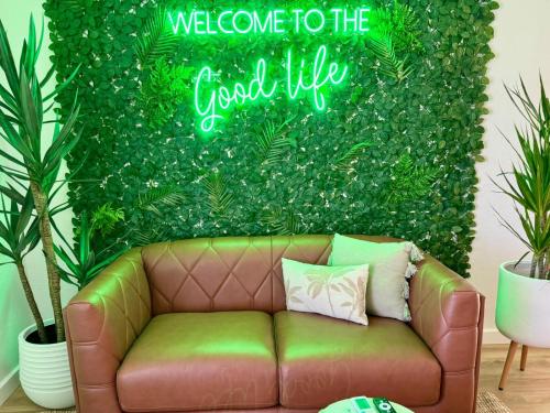 a couch in front of a green wall with a welcome to the good life at Barossa Palms Motel in Nuriootpa