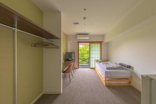a bedroom with a bed and a desk with a computer at LEU Guest House in Nasushiobara