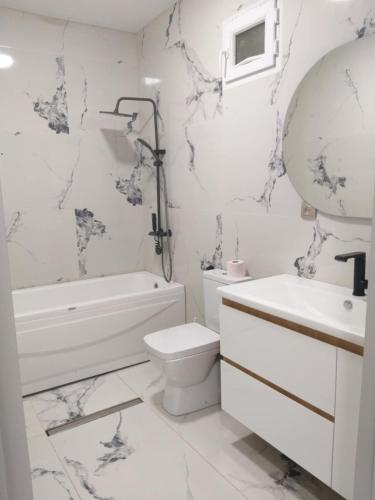 a white bathroom with a toilet and a tub and a sink at Goga Guest House in Kvariati