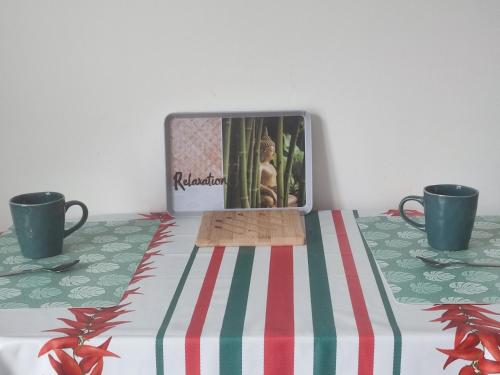 a television sitting on top of a table with two cups at studio cosy la Dacquoise centre-ville internet haut-débit in Dax