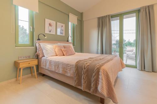 a bedroom with a large bed and a balcony at Alkyoni luxury apartments Katakolo in Katakolon
