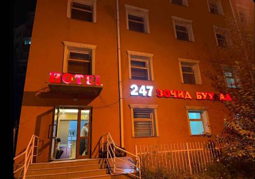 an orange building with a neon hotel sign on it at 247 hotel in Ulaanbaatar