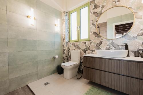 a bathroom with a sink and a toilet and a mirror at Alkyoni luxury apartments Katakolo in Katakolon