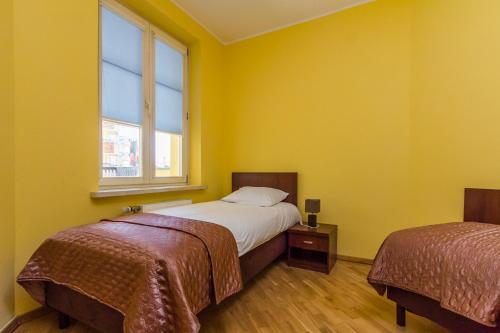 a yellow room with two beds and a window at Apartament Stare Miasto 2 in Elblag