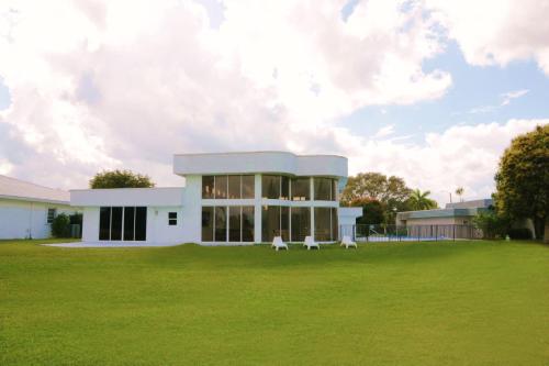 a white building with two white chairs in a field at The Monochrome Villa in Fort Lauderdale