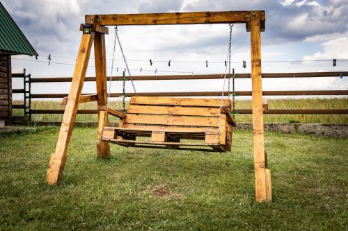 a wooden swing in a field with a fence at Guest house Holiday in Žabljak